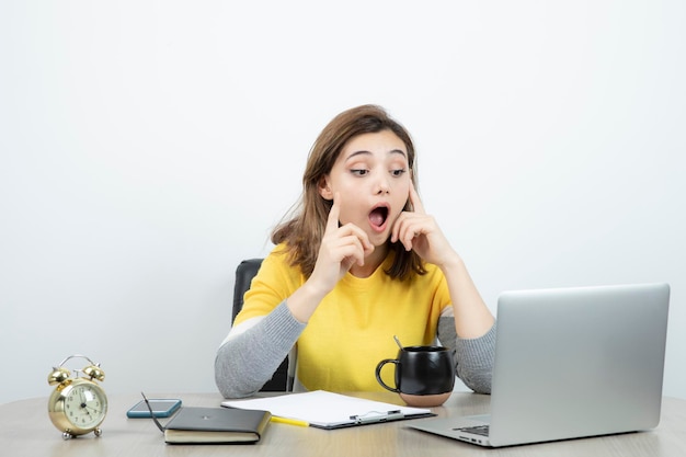 Foto van vrouwelijke kantoormedewerker zittend aan de balie met laptop. Hoge kwaliteit foto