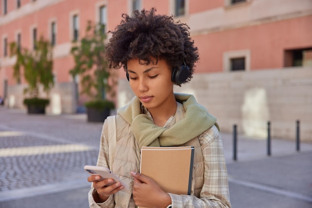 Foto van vrouwelijke student keert terug naar universiteit nadat quarantaine notitieblokken bij zich heeft die op smartphonescherm zijn gericht