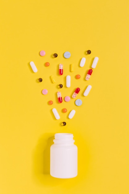 Foto van witte fles met verschillende veelkleurige pillen Medicijnen tegen ziekte hoofdpijn griep of verkoudheid