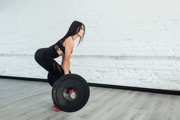 Foto foto van zelfverzekerde jonge vrouw gewichtheffen training bij sportschool terug te draaien.