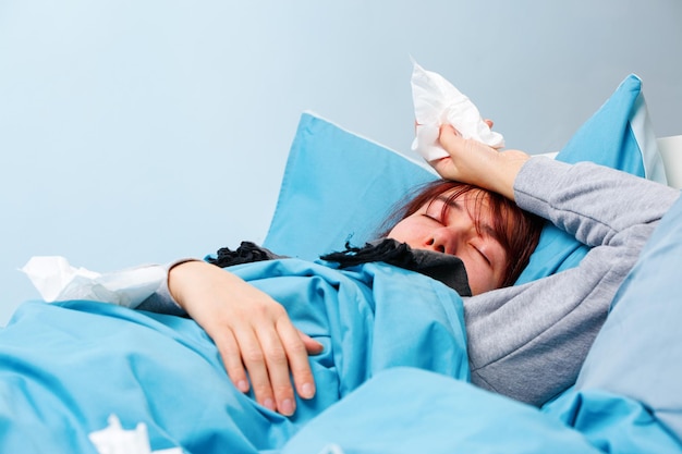 Foto van zieke vrouw met papieren zakdoeken die op bed liggen