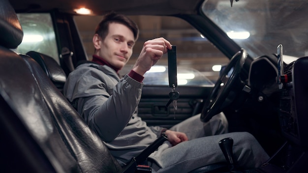 Foto foto van zijkant van mannelijke bestuurder met sleutels in auto