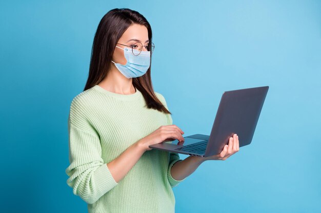 Foto van zoekstatistieken voor slimme meisjes op laptop draagt blauw gezichtsmasker geïsoleerd over blauwe kleur achtergrond