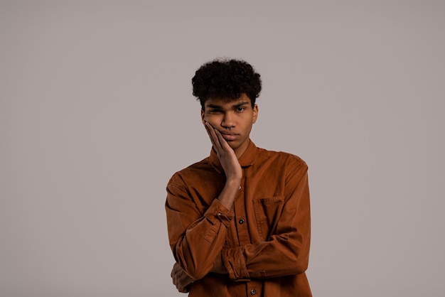 Foto van zwarte man ziet er verveeld uit en is nergens in geïnteresseerd. Man draagt shirt, geïsoleerde grijze kleur achtergrond.