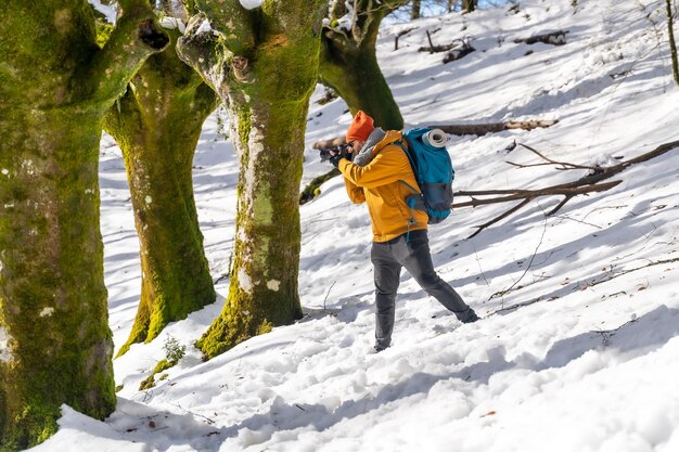 Fotograaf die een trekking doet met een rugzak die foto's maakt van een beukenbos met sneeuwpret en winterhobby's