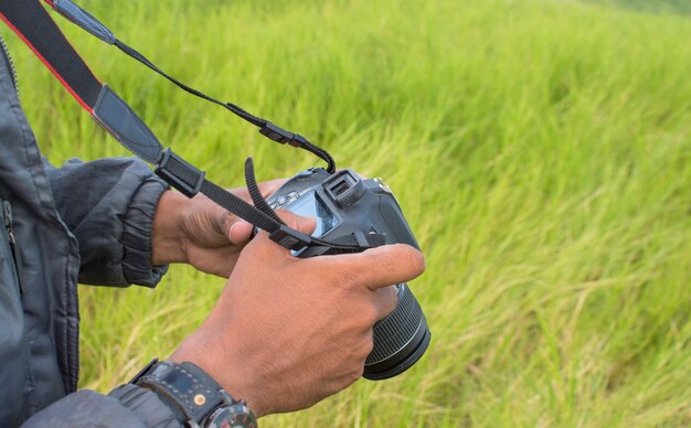 Fotograaf die zijn camera controleert, jonge man die zijn fotocamera controleert, close-up van een jonge man die zijn fotocamera controleert