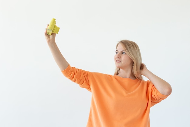 Fotograaf, hobby en vrije tijd concept - Jonge blonde vrouw met retro camera op witte muur