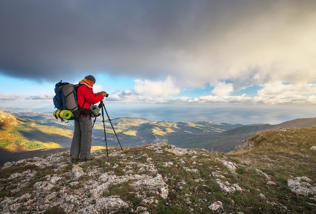 Fotograaf maakt foto's op de top van de berg in de herfst. Reiziger met rugzak op bergtop