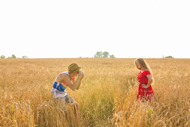 Fotograaf met camera fotograferen van jonge mooie vrouw in het veld.