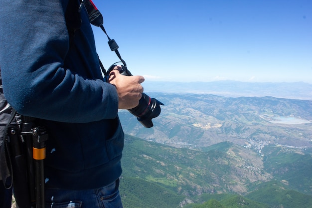 Fotograaf met camera maakt foto op de top van de berg onder de blauwe lucht