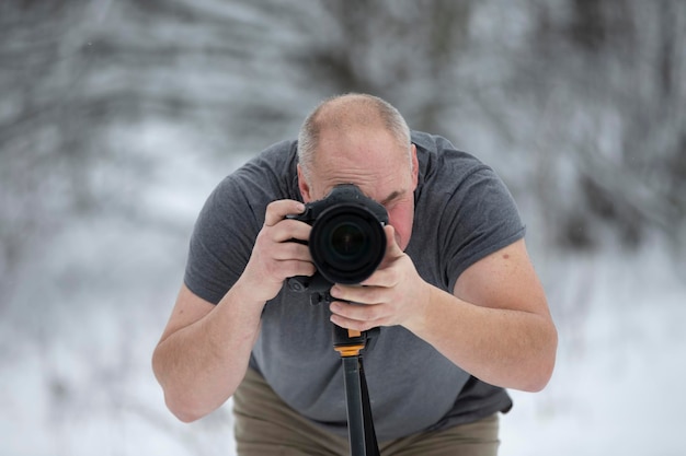 Fotograaf met een camera in het winterbos Oudere mannelijke fotograaf