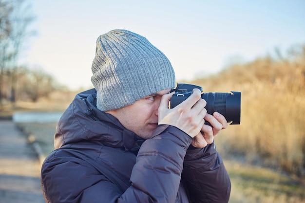 Fotograaf met hoed maakt een foto op zijn camera in het winterpark