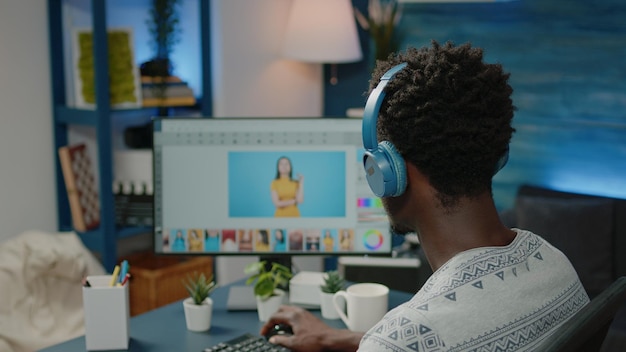 Fotograaf retoucheert foto's op de computer en draagt een koptelefoon. man aan het werk als media-illustrator die bewerkingswerk doet op de monitor voor fotografieproductie. afbeeldingseditor met app