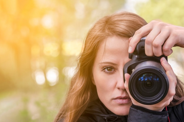 Fotograafmeisje, close-upportret. Het meisjesmodel maakt foto's, kijkt naar de kijker en in de lens van de buitencamera. rood haar ontwikkelen, copyspace