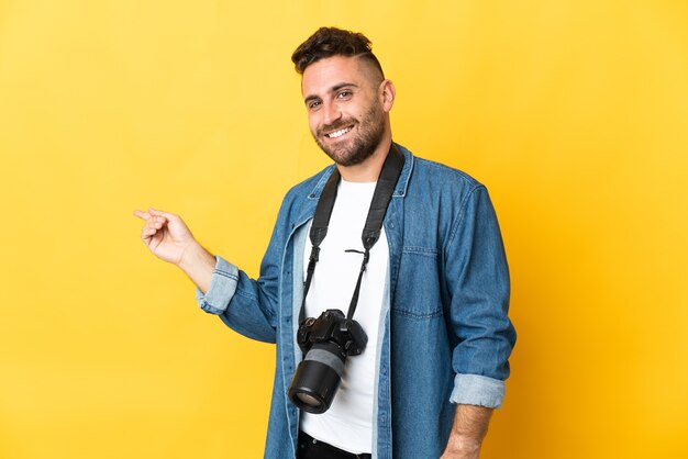 Fotograafmens geïsoleerd op gele achtergrond wijzende vinger naar de zijkant