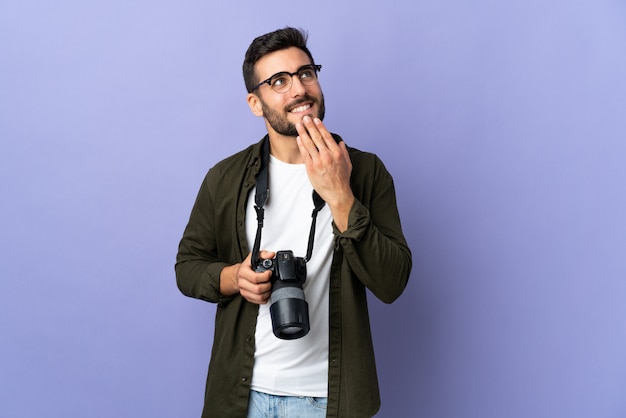 Fotograafmens over geïsoleerde purpere muur die omhoog terwijl het glimlachen kijkt