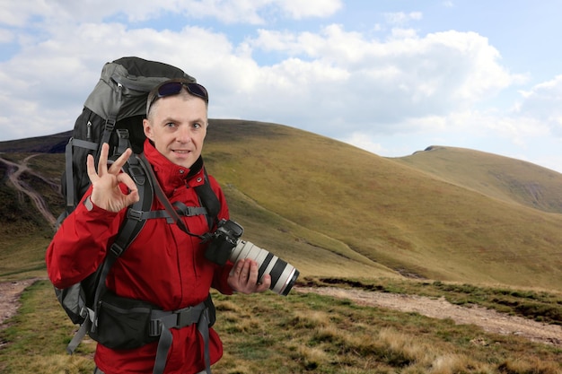 Fotograafreiziger in het rode jasje op de olifantsberg toont hand OK-teken