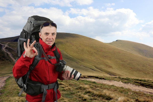 Fotograafreiziger in het rode jasje op de olifantsberg toont hand ok-teken