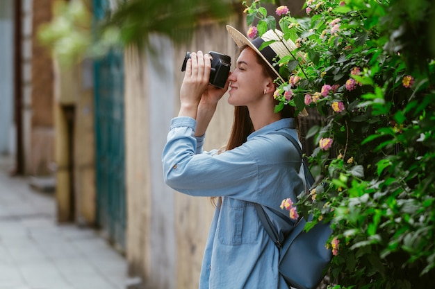 Fotograafreiziger in hoed maakt foto's van bezienswaardigheden tijdens een wandeling langs de straat van een Europese stad. Vakantie en toerisme