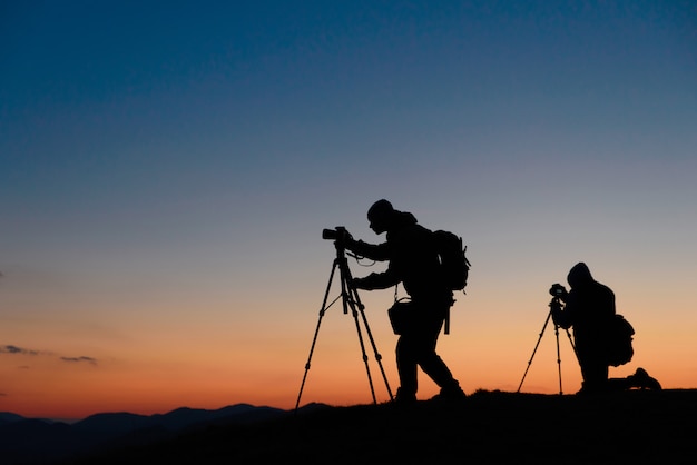 Fotografen werken met camera's bij zonsondergang in de natuur