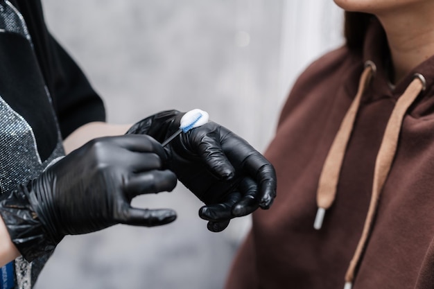 Fotograferen in een schoonheidssalon meester wenkbrauwkunstenaar veeg de borstel over het reinigingsschuim om de procedure op de wenkbrauwen van het model uit te voeren