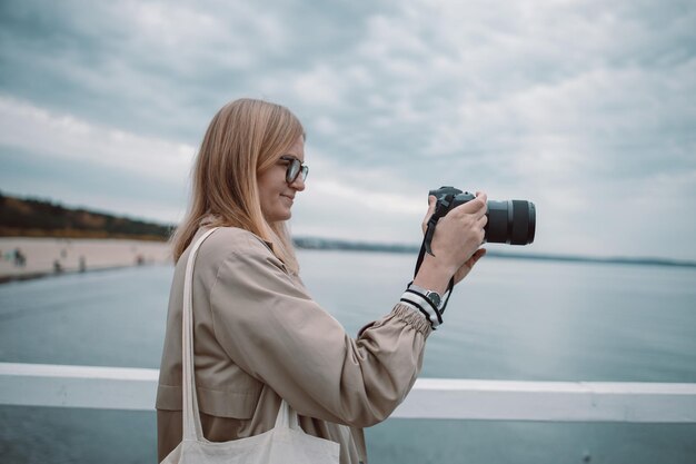 Fotografie en reizen jonge vrouw in hoed met camera zittend op houten vissteiger met beautif