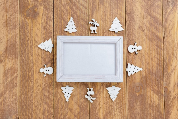 Fotokader tussen Kerstdecoratie, met figuren op een bruine houten tafel. Bovenaanzicht, frame om ruimte te kopiëren