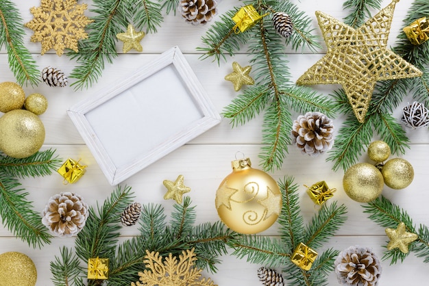 Fotokader tussen Kerstdecoratie, met gouden kleurenballen en ster op een witte houten tafel. Bovenaanzicht, frame om ruimte te kopiëren