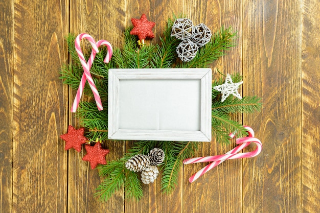 Fotokader tussen Kerstmisdecoratie, met sterren en suikergoedriet op een bruine houten lijst. Bovenaanzicht, frame om ruimte te kopiëren.