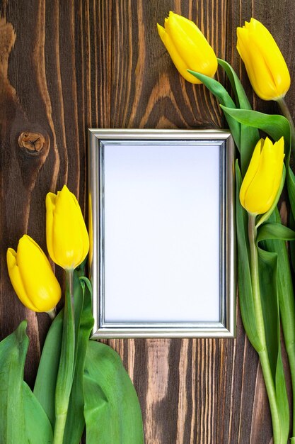 Fotolijst op een houten ondergrond in een orkestratie van gele tulpen