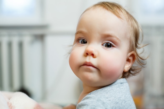 Fotoportret van een babymeisje met roze wangen. baby komt overeind