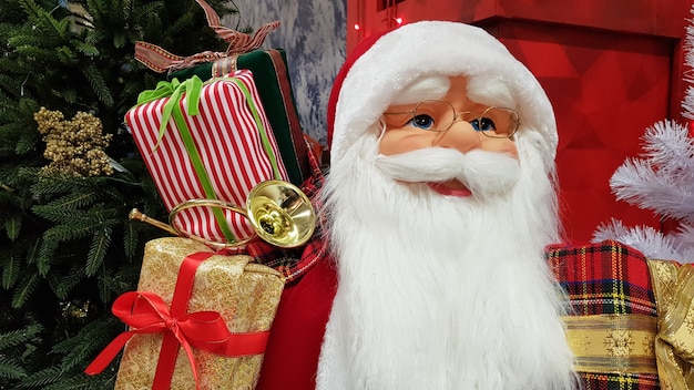 Fotoportret van een vrolijke speelgoedpop Santa Claus met een zak cadeaus symboliseert de komst van Kerstmis en Nieuwjaar. Feestelijke stemming, vakantieconcept.