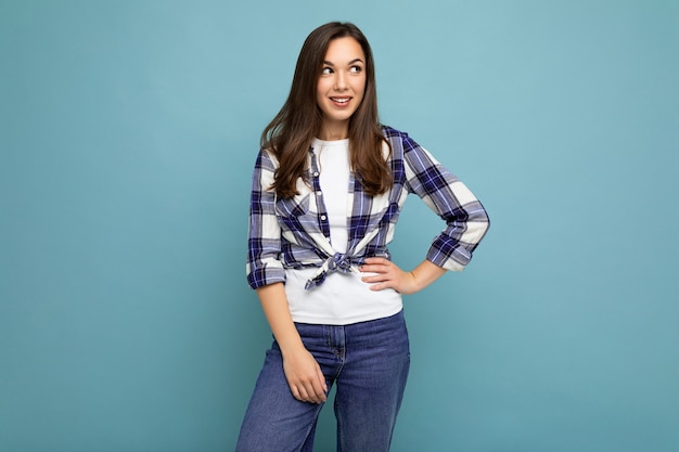 Fotoportret van jonge mooie glimlachende hipster donkerbruine vrouw in trendy blauw en wit overhemd en