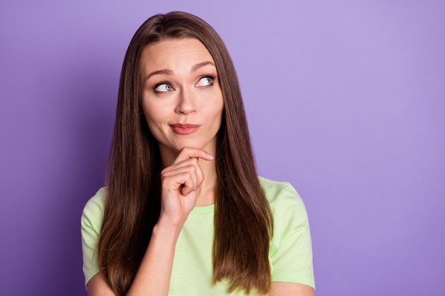 Fotoportret van nieuwsgierige vrouw die de kin van het gezicht aanraakt met vinger geïsoleerd op een levendige paars gekleurde achtergrond