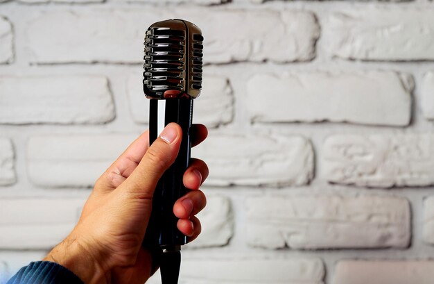 fotorealistische hand met vintage microfoon op witte bakstenen achtergrond