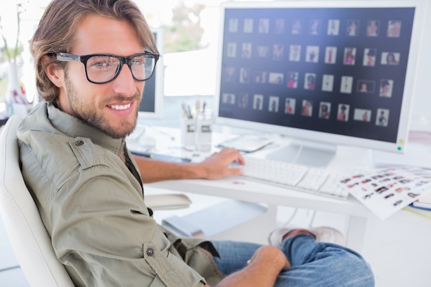 Fotoredacteur draaien en glimlachen aan zijn bureau