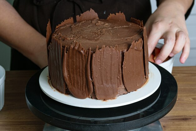 Fotoshoot met chocoladetaart die wordt versierd. chocoladetaart bedekt met aardbeien, verse basilicumblaadjes, bramenjam en chocoladeplaten rondom.