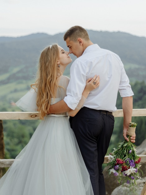 Fotoshoot van een verliefd stel in de bergen. Het meisje is gekleed als een bruid in een trouwjurk.