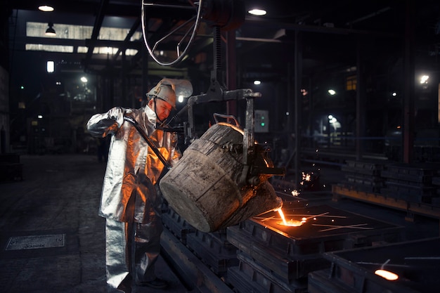 Foundry worker pouring liquid steel into molds.