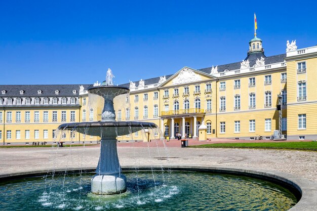 Fountain in city against clear blue sky