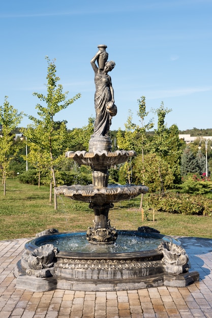 投手を持つ女性の都市公園の噴水