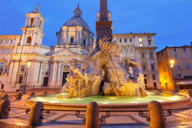 Fountain of the Four Rivers and Sant Agnese Church on the famous Piazza Navona Square during morning blue hour, Rome, Italy.