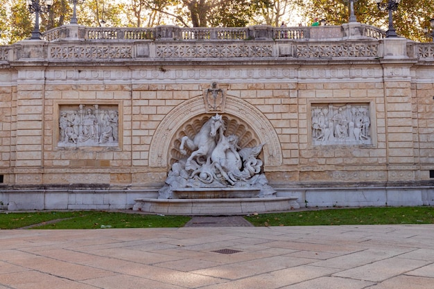 A fountain with a horse on it in front of a building with the word " love " on it.