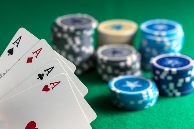 Four aces and poker chips on green felt background