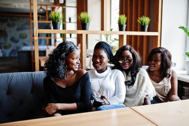 Four african american girls sitting on table at cafe