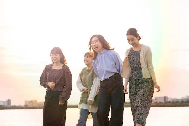 写真 夕暮れ時に楽しく話している4人のアジアの若い女性