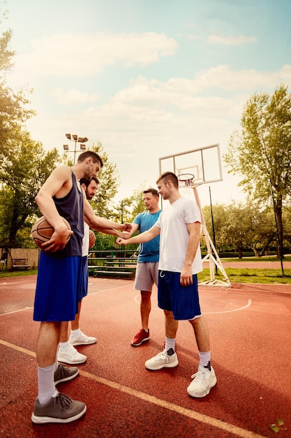 Four basketball players having a sports greeting before match. They are fist bump.