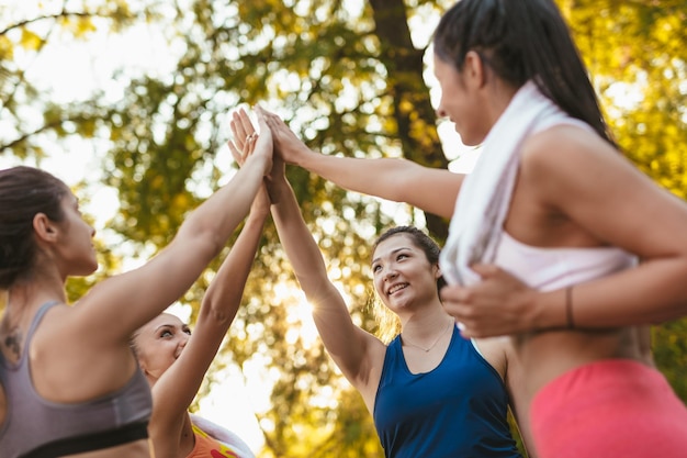 Foto quattro belle amiche che danno il cinque dopo un buon allenamento nel parco.