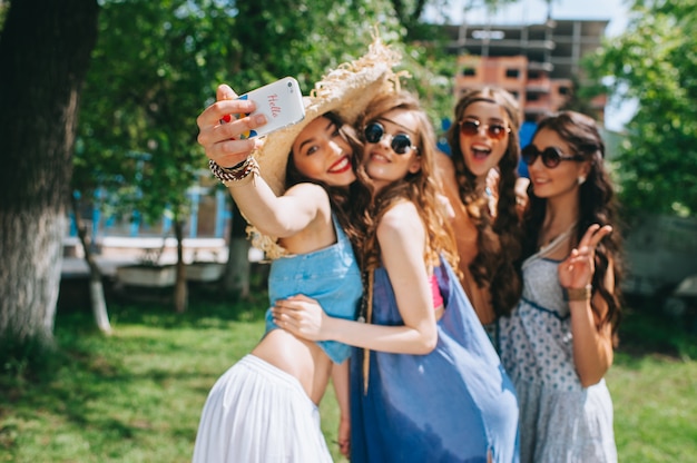 Quattro belle ragazze hippy facendo selfie all'aperto