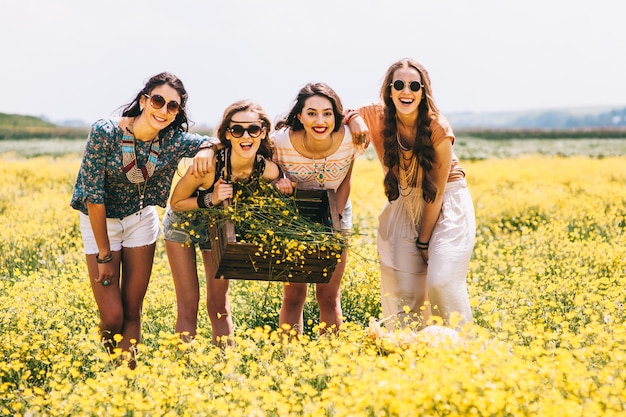 four beautiful hippie girl in a field of yellow flowers